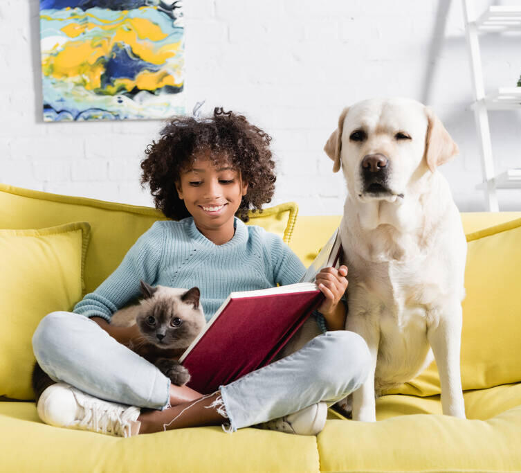 Child sitting with a dog and cat